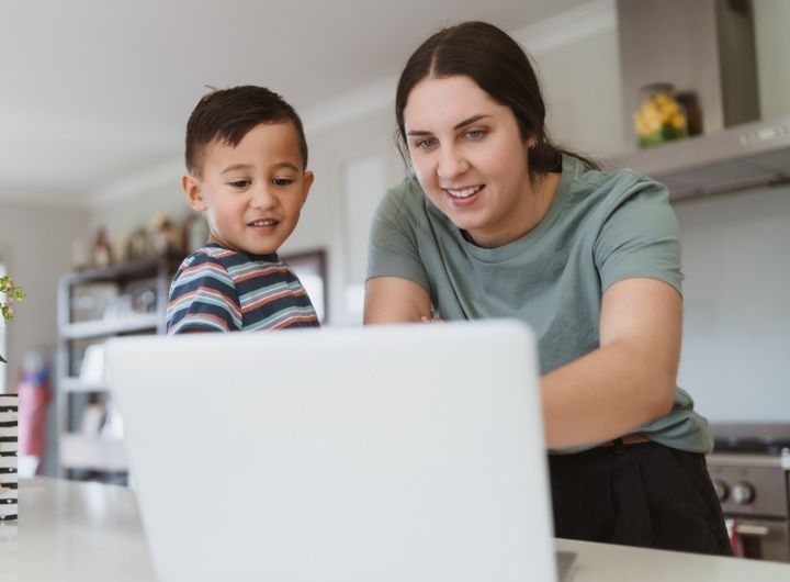 mum and young child point at laptop screen