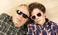 dad and son lying on floor wearing sunglasses, headphones