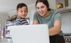 mum and young child point at laptop screen